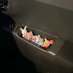 some little stuffed animals are sitting in the car's door handle drawer compartment holder