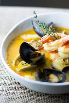 a white bowl filled with seafood and mussels on top of a cloth covered table