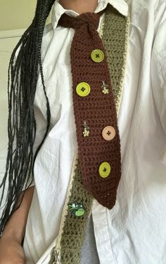 a person wearing a tie with buttons on it and dreadlocks around their neck