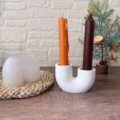 a couple of candles sitting on top of a wooden table next to a white vase