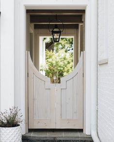 a white door with a lantern hanging from it's side next to a potted plant