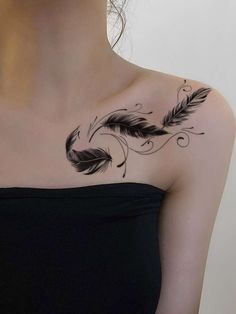 a woman with a tattoo on her chest has a black feather and swirls design