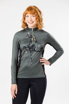 a woman with red hair wearing a green shirt and black leggings stands in front of a white background