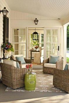 a porch with wicker furniture and green vases on the table in front of it