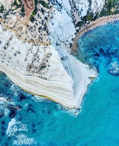 an aerial view of the blue water and land in front of some mountains with snow on them