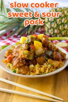 a white plate topped with meat and pineapples next to chopsticks on a table