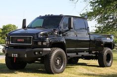 a black truck parked on top of a lush green field