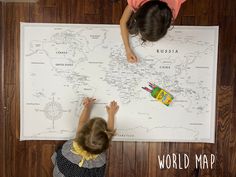 two children are playing with a map on the floor