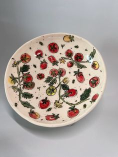 a white plate with red and yellow tomatoes on it's rim, sitting on a gray surface