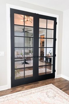 a living room with two doors and a rug on the floor in front of it