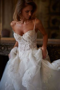 a woman in a white wedding dress is looking down at her hand on the waist