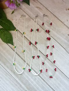 three beaded necklaces with red, green and yellow beads on a white wooden surface