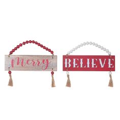 two wooden signs with tassels hanging from the sides, one saying merry and the other saying believe