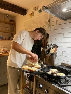 a young man preparing food on top of a stove