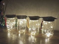 four mason jars with lights in them on a table