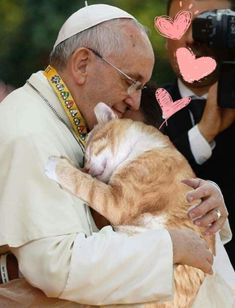 a man holding a cat in his arms as he is being hugged by another man