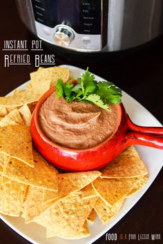 a plate with tortilla chips and a pot of refried beans