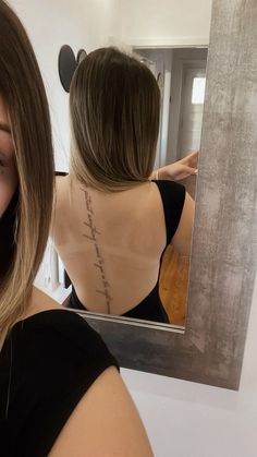 a woman looking at her back in front of a mirror that has writing on it