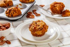 several muffins on white plates with pecans scattered around them