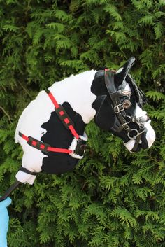 a toy horse is in the middle of some bushes and trees with gloves on it's head