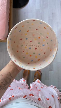 a person holding up a bowl with the word happiness written on it