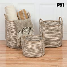 three woven baskets sitting on top of a wooden floor