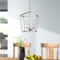 a dining room table with some fruit on it and a light fixture hanging from the ceiling