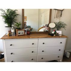 a white dresser topped with lots of drawers and a large mirror on top of it