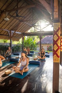 a group of people sitting on yoga mats in a room with wooden floors and ceilings