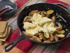 a skillet filled with potatoes and cheese on top of a table