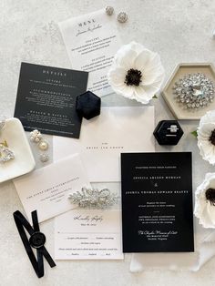 the wedding stationery is laid out on top of each other with flowers and jewelry