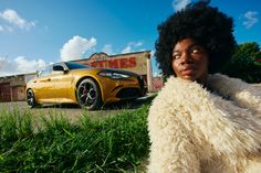 a woman with an afro standing in front of a yellow car