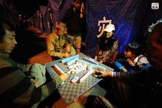 a group of people sitting around a table with some food on top of it,