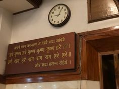 a clock mounted to the side of a wall next to a sign with writing on it