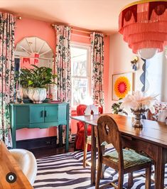 a dining room with pink walls and floral curtains