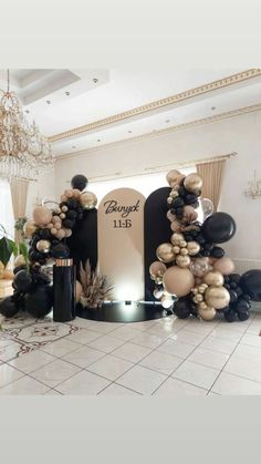 a room filled with balloons and decorations in black, gold and white colors on the floor