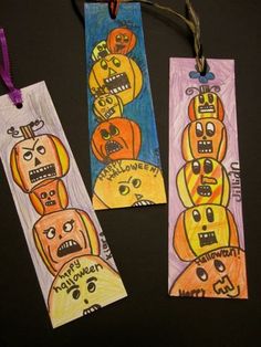 three halloween bookmarks with faces drawn on them and string attached to the tags that say happy halloween