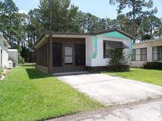 two mobile homes are shown in front of some trees and grass, one has a green door