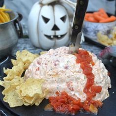 a black plate topped with chips and salsa next to a white jack - o'- lantern