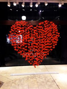 a large heart made out of red hearts in front of a glass window with the words love you written on it