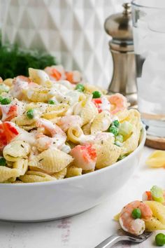 a white bowl filled with pasta salad and peas