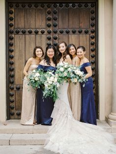 a group of women standing next to each other in front of a door holding bouquets