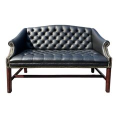 a black leather couch sitting on top of a wooden frame with studded trimmings