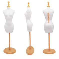 three white mannequins on wooden bases with gold accents