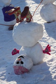 snowmen with hats and scarves on their heads in the snow