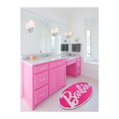 a bathroom with pink vanity and rug that says barbie