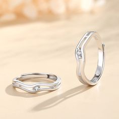 two silver rings sitting next to each other on a table