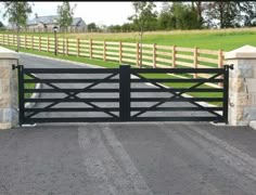 a gated driveway leading to a grassy field