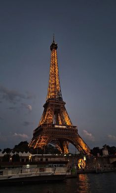 the eiffel tower lit up at night in paris, france with boats passing by