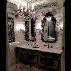 a bathroom with two sinks, mirrors and chandelier